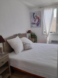 a bedroom with a bed with white sheets and a window at CHEZ JACQUES ET MANUE in Six-Fours-les-Plages