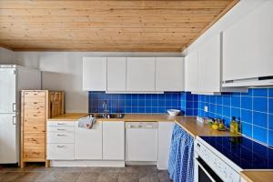a kitchen with white cabinets and blue tiles at Cozy Scandinavian apartment central in Oslo - free parking and close to many amenities in Grorud