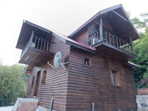 ein Holzgebäude mit einer Uhr und einem Balkon in der Unterkunft Diamond Tree House in Macka