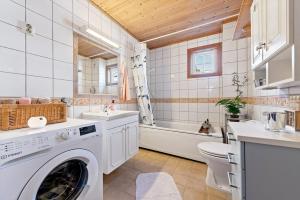 a bathroom with a washing machine and a sink and a tub at Cozy Scandinavian apartment central in Oslo - free parking and close to many amenities in Grorud