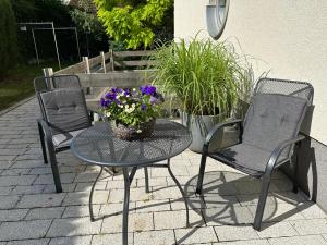 2 Stühle und ein Tisch mit einem Blumenkorb in der Unterkunft Monopol Apartments in Wernigerode