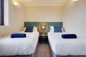 Bright and Cosy house with 3 bedroom 3 bathrooms في بورنموث: سريرين مع وسائد زرقاء في الغرفة
