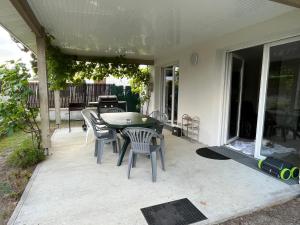 une terrasse avec une table et des chaises dans une maison dans l'établissement La cazalaise, à La Teste-de-Buch