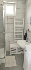 a white bathroom with a sink and a shower at Grey Line Guesthouse in Badacsonytördemic