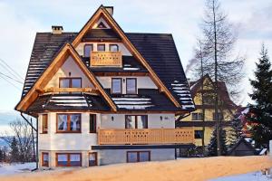 a house with a gambrel roof with snow on the ground at Willa Parzenica in Bukowina Tatrzańska