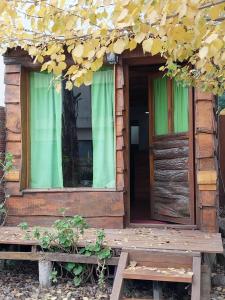 a wooden cabin with green curtains and a bench at La Cabaña in Tandil