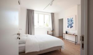 een witte slaapkamer met een groot bed en een raam bij Le Charbonnage in Genk