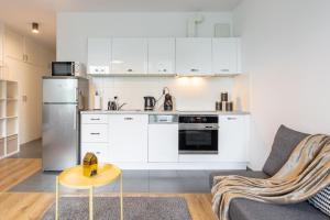 a kitchen with white cabinets and a couch and a table at Golden Apartments Warsaw - Big and Bright Stylish Apartments - City Center - Pereca in Warsaw