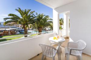 a balcony with a table and chairs and palm trees at Jutlandia Family Resort in Santa Ponsa