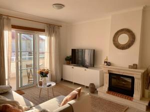 a living room with a couch and a television at Nalu House Baleal - by the beach in Baleal