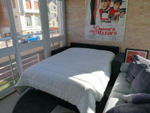 een bed en een bank in een kamer met een raam bij appartement 50 m2 vue mer in Villers-sur-Mer