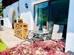 un patio con tavolo, sedie e fiori di Chalet Bernardi Apartments a Ortisei
