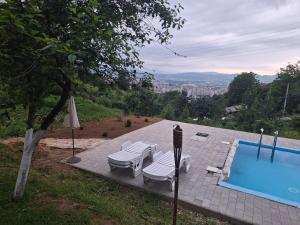 a swimming pool with two lounge chairs and an umbrella at Tent Camping in Sarajevo