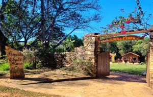 - un accès à un jardin avec un mur en pierre et un panneau dans l'établissement Pousada Muro de Pedra, à São Thomé das Letras