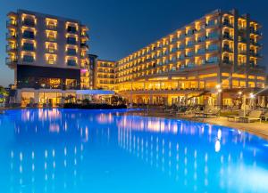 a hotel with a large swimming pool in front of a building at NissiBlu Beach Resort in Ayia Napa