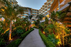 a walkway through a resort with palm trees and plants at NissiBlu Beach Resort in Ayia Napa