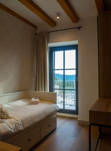 ein Schlafzimmer mit einem Bett und einem großen Fenster in der Unterkunft Villa Marlea Konavle Dubrovnik in Gruda