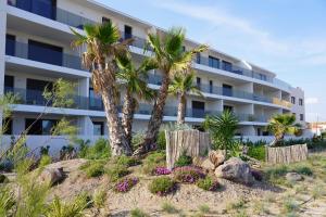 een appartementencomplex aan het strand met palmbomen en bloemen bij sur la plage ! in Valras-Plage