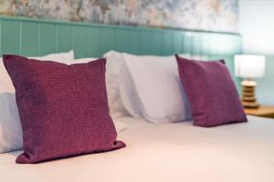 Una cama con almohadas moradas y blancas. en The Queens, en Carlisle