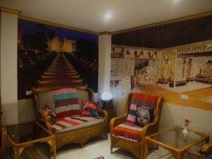 una habitación con 2 sillas y un cuadro en la pared en Venus hotel luxor 日本人 大歓迎, en Luxor