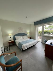 ein Schlafzimmer mit einem Bett, einem Stuhl und einem Fenster in der Unterkunft Hotel Excelsior Bay in Malcesine