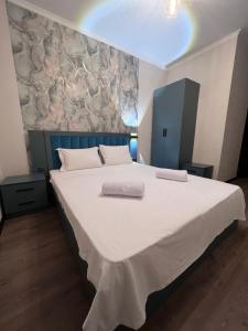 1 cama blanca grande con 2 toallas en Cosmos Hotel, en Bishkek