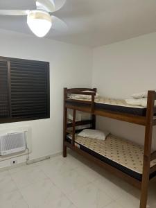 two bunk beds in a room with a ceiling fan at NOVO pitangueiras service 2, dois dormitórios, 100 m da praia, duas vagas de garagem, completo in Guarujá