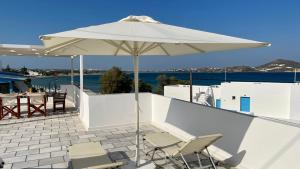 una sombrilla blanca en un patio con sillas y mesa en Summer Times Studios, en Naxos Chora