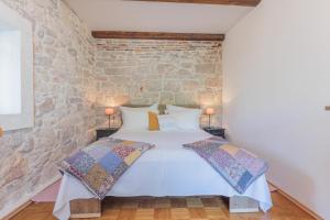 a bed in a room with a stone wall at Traditional holiday house by the sea in Preko