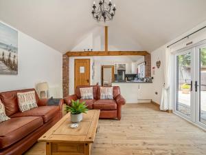 uma sala de estar com sofás de couro e uma mesa em Little Tree Cottage em Felmingham