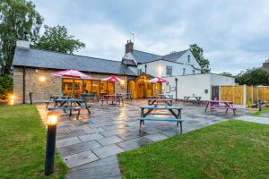 a patio with picnic tables in front of a building at The Queens in Carlisle