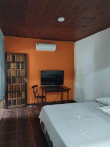 a bedroom with a bed and a desk with a television at Rancho Hanna - Pousada, Camping e Comidaria in Iporanga