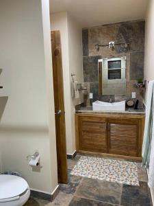 y baño con aseo y lavabo con microondas. en Hermosa casita con vista al río., en San Cristóbal de Las Casas