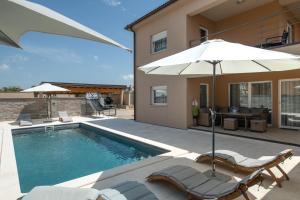 ein Swimmingpool mit zwei Stühlen und einem Sonnenschirm in der Unterkunft Villa Maslina in Vodnjan + 66 Fotos