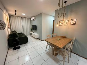 uma sala de jantar com uma mesa e uma sala de estar em 02 QUARTOS, a 200 metros da PRAIA de PAJUÇARA em Maceió