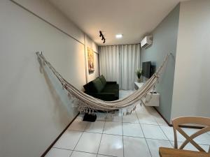 uma rede de descanso suspensa numa sala de estar com um sofá em 02 QUARTOS, a 200 metros da PRAIA de PAJUÇARA em Maceió