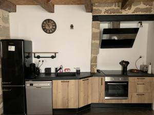 a kitchen with a black refrigerator and wooden cabinets at appartement de charme centre historique de Brive in Brive-la-Gaillarde