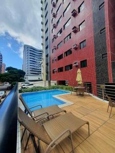 uma varanda com cadeiras e uma piscina em um prédio em 02 QUARTOS, a 200 metros da PRAIA de PAJUÇARA em Maceió