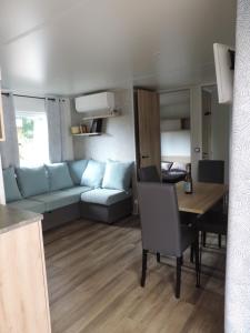 un salon avec un canapé et une table dans l'établissement Mobil home Lège Cap Ferret Camping 4 étoiles Les Viviers, à Lège-Cap-Ferret