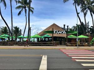 um restaurante com guarda-sóis verdes ao lado de uma rua em 02 QUARTOS, a 200 metros da PRAIA de PAJUÇARA em Maceió