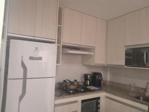 a kitchen with white cabinets and a white refrigerator at Beira-mar in Santos