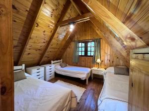 1 dormitorio con 2 camas en una cabaña de madera en Los Plátanos cabañas & suites en Moreno