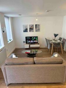 a living room with a couch and a table and a tv at New Build 2 Bedroom Luxury Apartment, Jewellery Quarter Birmingham in Birmingham