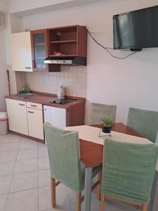 a kitchen with a table and chairs and a television at Apartmani Ante 1 in Drašnice