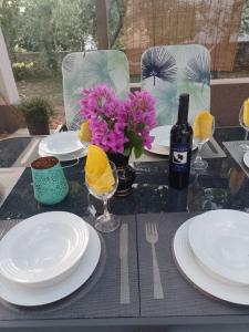 una mesa con platos blancos y una botella de vino y flores en Apartman Sutivan, en Sutivan
