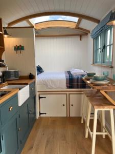 a kitchen with a bed and a table in a room at Toms Hut and Robins Rest Shepherd Huts near Wadebridge in Wadebridge