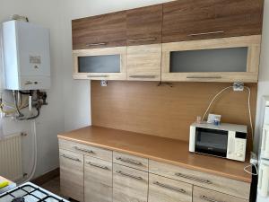 a kitchen with wooden cabinets and a microwave oven at M35 4s Debrecen Apartman in Debrecen