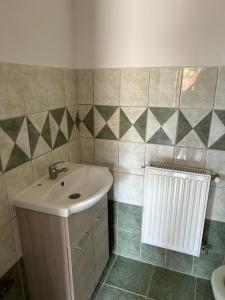uma casa de banho com um lavatório e um radiador em M35 4s Debrecen Apartman em Debrecen