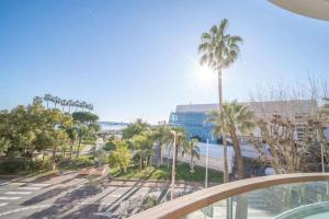 d'un balcon avec vue sur la plage et les palmiers. dans l'établissement PACA Properties 7C2 - appartement 3 chambres, à Cannes