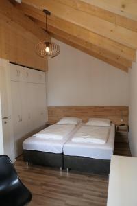 ein Schlafzimmer mit 2 Betten und einem Stuhl darin in der Unterkunft Casa Safra in Kötschach